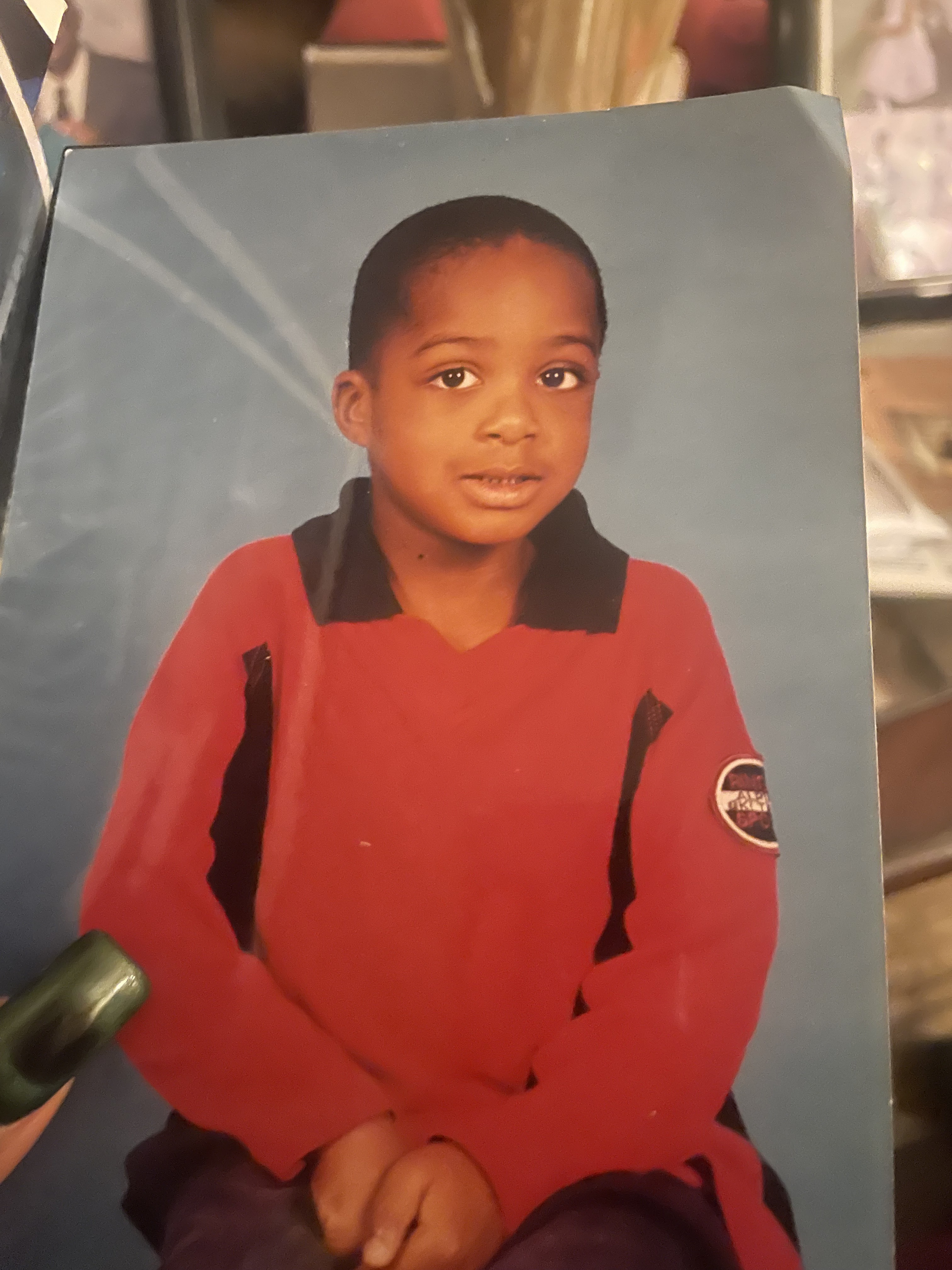 Official input: a photographed printed portrait of a child in a red shirt